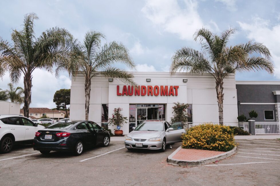 Laundromat with palm trees and cars.
