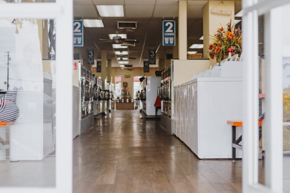 A large room with many white appliances and wooden floors.