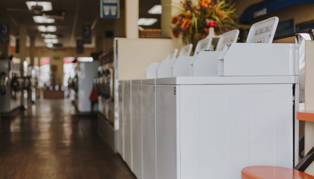 A row of white washer dryers in a room.